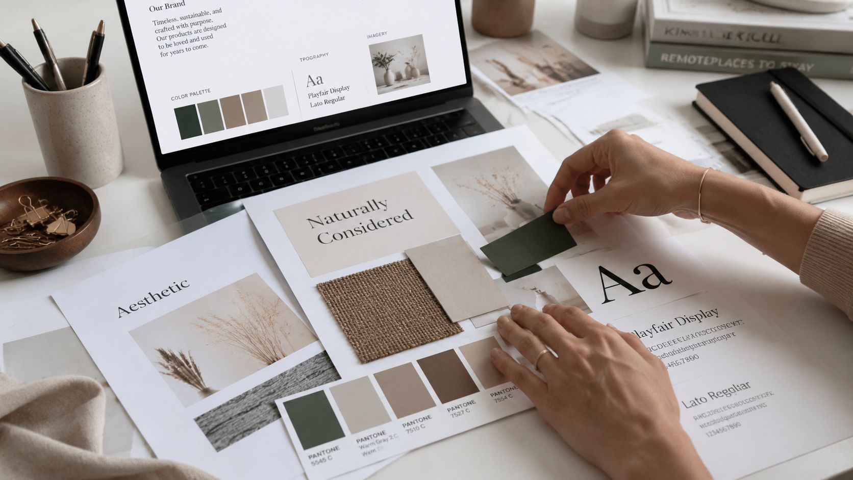 A professional interior designer creating a brand style guide template on a wooden desk.